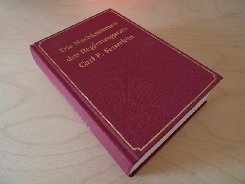 Stammbuch "Die Nachkommen des Regierungsrats Carl F. Feuerlein, mit rotem Einband und goldener Schrift.